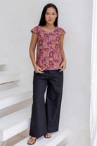 Woman wearing a floral cap sleeve top  blending pink, maroon, brown, peach and khaki palette.