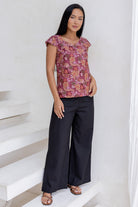 Woman standing in a 100 percent cotton floral print top with cap sleeves, round neckline and keyhole cutout.