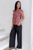 Model posing in a floral print tailored cotton top with cap sleeves, round neckline and length sitting at the hip 