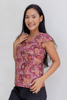 A woman wears a 100% cotton tailored top with short cap sleeves and a round neckline with a keyhole cutout, paired with black cotton pants