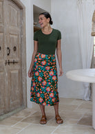 Woman wearing a basic top and olive green based skirt in a indoor setting