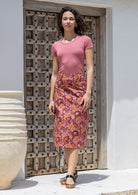 Woman wearing floral print mid length skirt with side zipper and belt loops.