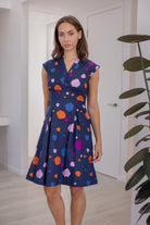 Woman wears 100% Cotton Bold Spotty Print Dress with tailored v-neckline, empire waistline, a-line skirt and side zipper