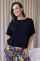 Woman wearing a black relaxed fit stretch rayon top with short sleeves and high round neckline