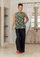 Woman wearing a 100% cotton green based floral sleeveless top with small pleated design, and buttoned mandarin collar.