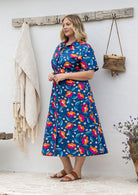 Model standing wearing a floral printed shirt dress with detachable fabric belt and short sleeves 