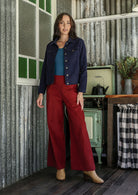 Woman in deep, rich, and slightly muted navy blue jacket and plain corduroy pants standing in a kitchen  