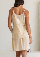 Back view of woman in a nude toned cotton voile above knee slip skirt with picot trim, paired with a matching cami