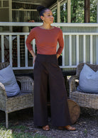 Woman in pink long sleeve top and brown cotton corduroy pants standing outdoors