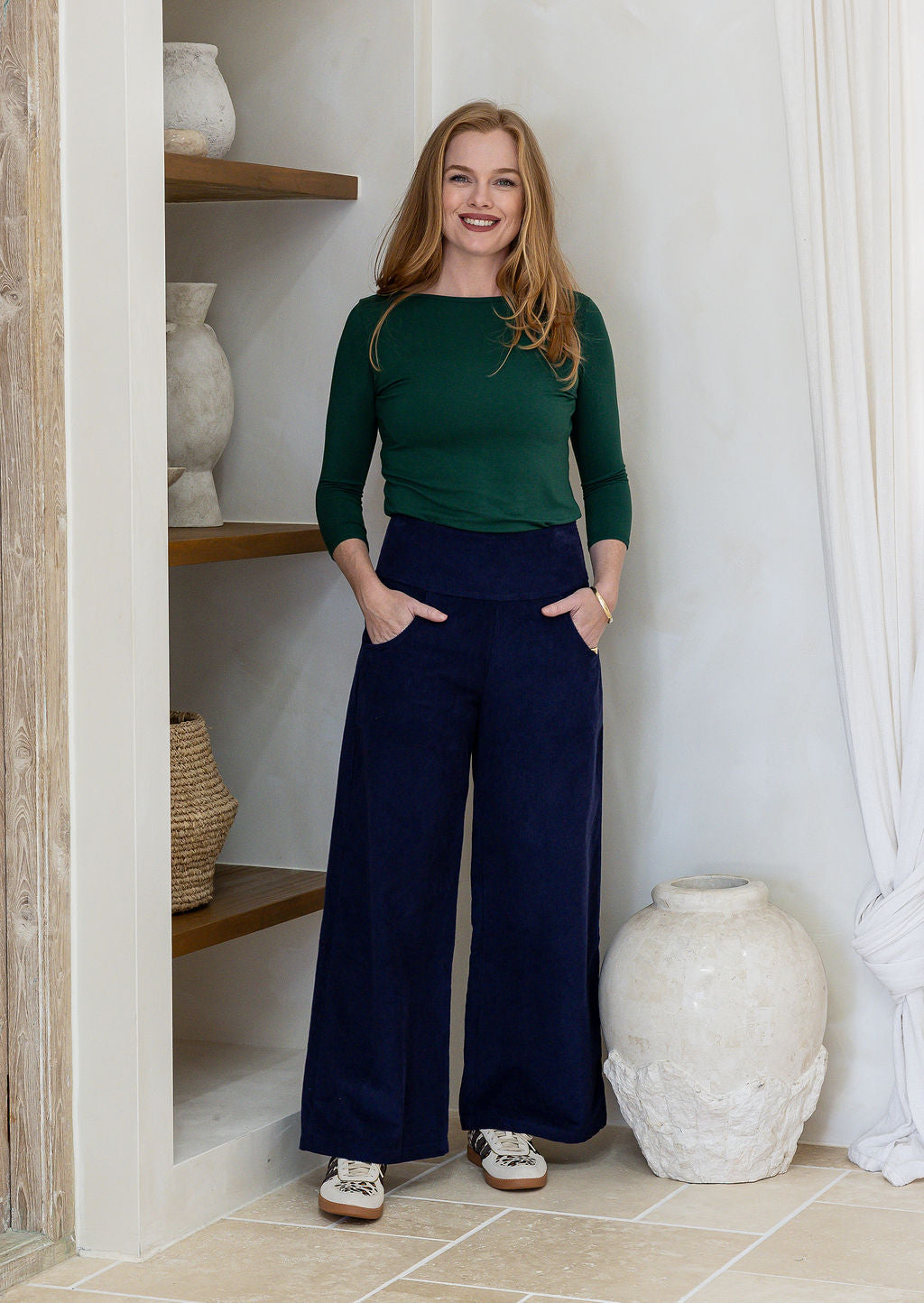 Woman wearing a corduroy wide leg pants in deep navy blue with both hand in pockets 