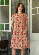 Model wearing a cotton V-neck short sleeve dress with empire waistline and  pocket.