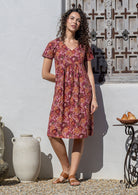 Model wearing a cotton V-neck short sleeve dress with empire waistline and  hand in pocket.