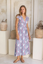 Woman wearing blue based floral print wrap around maxi dress 100% rayon