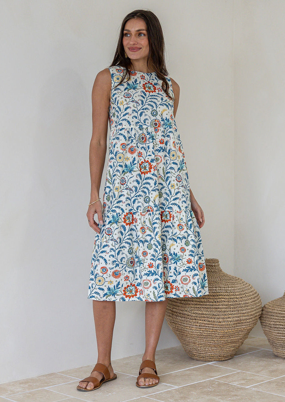 Model wears 100% cotton sleeveless midi dress with high round neckline, tiered design and pockets in white based  floral print