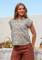 Woman wearing a slim fit button up shirt with shell buttons, structured collar and folded cuff sleeves