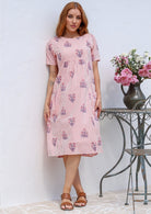 Woman wearing a 100% cotton Pink striped midi dress with floral print, short sleeves. 