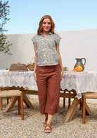 Woman wearing a 100% cotton Floral print short-sleeve button-up shirt worn with rust pants. 