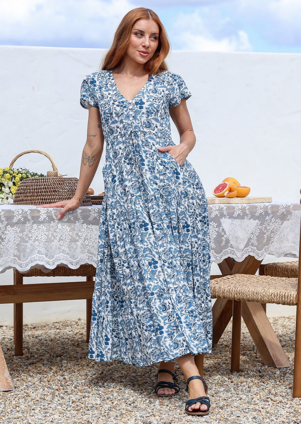 Blue and white floral print maxi dress with short sleeves and V-neck, worn by model standing outdoors.
