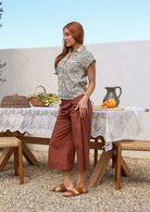 Woman standing sideways wearing slim fit cotton shirt in white based floral print with plain pants