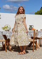 Woman wearing a 1950's style short sleeved, button through cotton dress and high round neckline with pockets