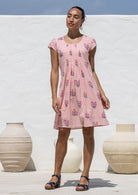 Woman poses in a 100% cotton pink striped white based floral dress with round neckline and cap sleeves
