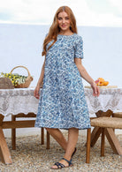 Woman wearing a 100% cotton white based blue floral print midi dress with short sleeves. 