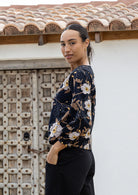 Woman wearing a black 100% cotton top with bishop sleeves and boat neckline in beautiful camellia print 