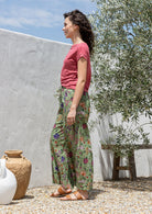 Side pose of model wearing wide leg, floral printed cotton pants with pockets and elastic waist at the back.