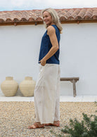 Woman wearing a blue top and white cotton pants with relaxed wide-leg fit, pockets and elastic at back of the waist.