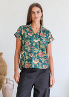 Woman poses in relaxed fit cotton short sleeve top with rolled cuffs sleeves, collar and V neckline.
