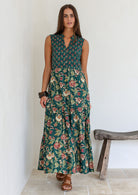 Model wears bottle green based floral cotton dress with pockets, 3/4 sleeves, V neck and mandarin collar.