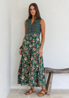 Model wearing a cotton three tiered maxi dress with  3/4 sleeves and buttoned bodice in combination of two green based floral prints.