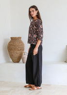 Woman stands sideways wearing relaxed fit, 100% cotton top in with loose 3/4 sleeves and wide round neckline.
