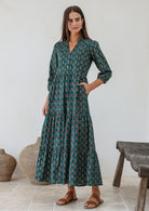 Woman wearing relaxed fit floral printed cotton maxi dress in green with 3/4 sleeves, pockets and three tiered skirt