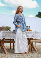 Woman wearing a 100% cotton white based  blue floral print top with white wide-leg pants. 
