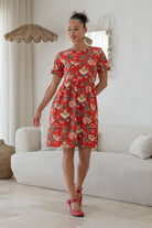 Woman wearing a above knee length floral cotton dress with short sleeves, pockets and round neckline 