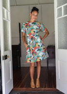 Woman wearing a relaxed fit, above knee length cotton dress with colourful floral print.