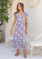 Woman wearing floaty rayon dress with elasticated V-neckline and a ruffle on the bottom third of skirt