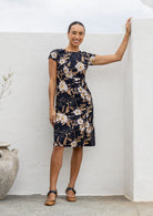 Woman wearing 100% cotton black based floral sundress with round neckline, cap sleeves, A line skirt and pockets