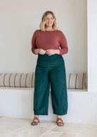 Woman wearing a cotton corduroy wide-leg dark green pants. 
