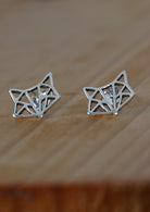 Origami Fox silver stud earrings on a wooden surface