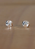 A pair of sterling silver star-shaped stud earrings laid on a wooden surface