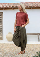 Woman wearing a rust-colored top and olive green harem style cotton pants with deep pockets, elasticated waist and ankles 