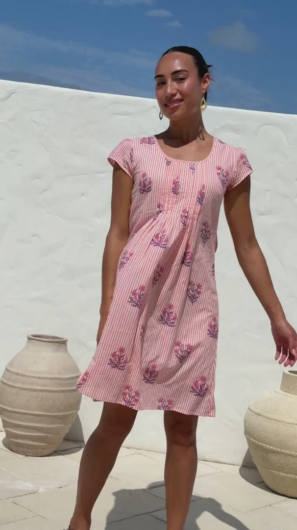 Video of a woman wearing a 100% cotton Pink striped floral print cap-sleeve dress with smocked waist. 
