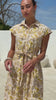 Video of a woman wearing a 100% cotton yellow floral print shirt dress with collar, cap sleeves, and tie waist. 
