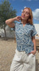 Video of woman poses in relaxed fit cotton short sleeve top with rolled cuffs sleeves, collar and V neckline.