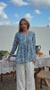 Video of a women wearing a white based blue floral print cotton top with pin tuck detail, long sleeves. 