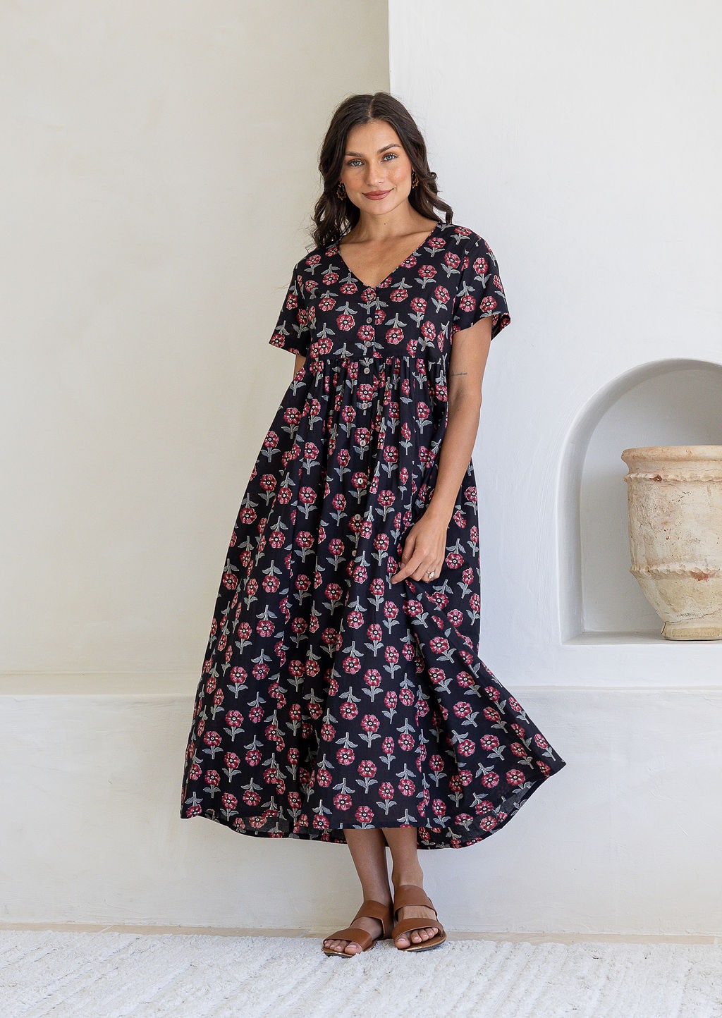 Woman posing in a relaxed fit, short sleeved, floral cotton dress with V- neckline, drawstring waist tie and pockets 