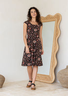 Model in knee length, black 100 percent cotton scoop neck Indian traditional style print dress with pockets and cap sleeves 