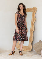 Model wearing a Indian traditional print dress with scoop neck, cap sleeves and piped detailing at the waist and pockets.